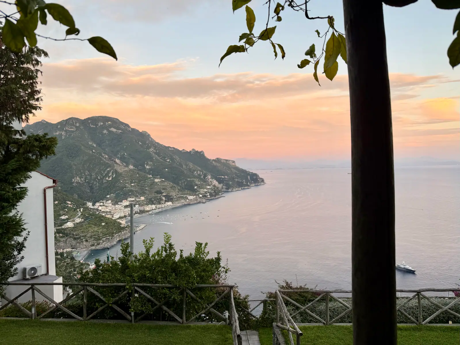 Sunset view from a terrace over a coastal town, mountains, and the sea on the Amalfi Coast.