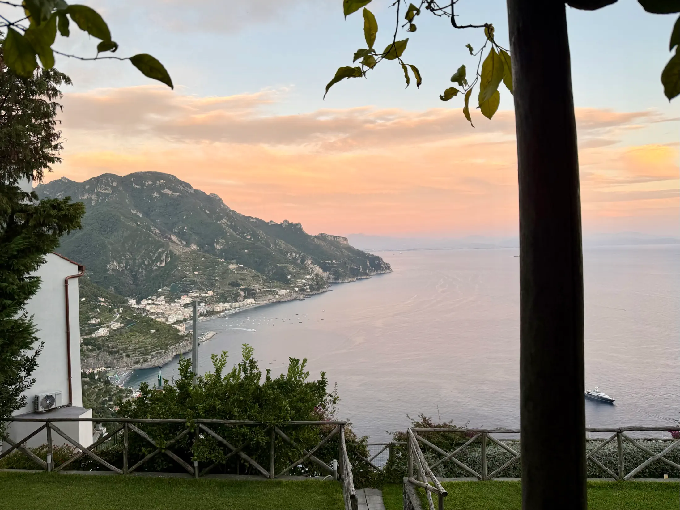 Sunset view from a terrace over a coastal town, mountains, and the sea on the Amalfi Coast.